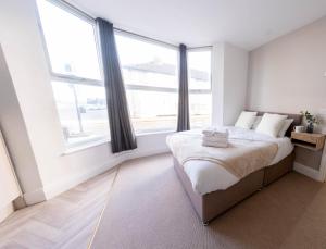 a white bedroom with a bed and large windows at Bowles Hotels in Redcar