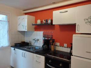 a kitchen with white cabinets and an orange wall at Spacieux T3 lumineux dans quartier historique avec wifi in Redon