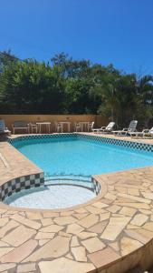 a large swimming pool with chairs around it at Pousada Barcarola in Búzios