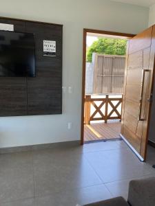 ein Wohnzimmer mit einem TV und einer Glasschiebetür in der Unterkunft Casa Vista Mar in Governador Celso Ramos