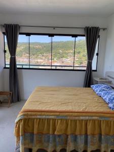 ein Schlafzimmer mit einem Bett und einem großen Fenster in der Unterkunft Casa Vista Mar in Governador Celso Ramos