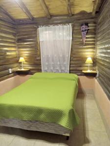 1 dormitorio con 1 cama verde y 2 lámparas en Peumayen Cabañas en Villa Las Rosas