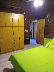 1 dormitorio con cama verde y armarios de madera en Peumayen Cabañas en Villa Las Rosas