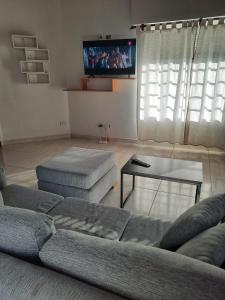 ein Wohnzimmer mit einem Sofa, einem Tisch und einem TV in der Unterkunft Necochea-Casa para hasta 4 personas! in Necochea