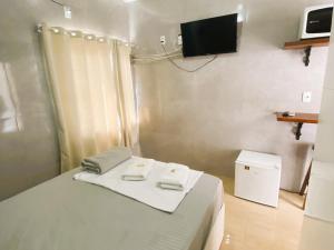 a bedroom with a bed with a tv on the wall at Estúdio e Suítes com Piscina, churrasqueira, AR Split, WIFI - 6x sem juros no cartão in Porto Belo