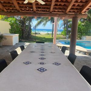 a white table with chairs and a swimming pool at Casa Mana: Beachfront Home w/pool on Playa Blanca in Zihuatanejo