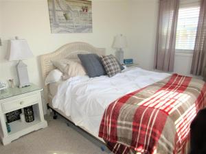 een slaapkamer met een bed met een geruite deken bij Upgraded 2nd Floor Duplex In The Heart Of Harvey Cedars Close To The Bay Beach And The Ocean, in Harvey Cedars