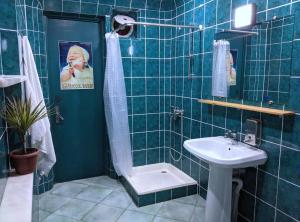 a blue tiled bathroom with a shower and a sink at Palm Hostel in Batumi