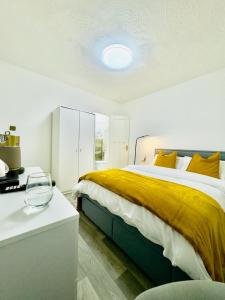 a bedroom with a large bed with a yellow blanket at Ensuite Luxury Bedroom In Purfleet in Purfleet
