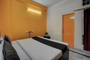a bedroom with a white bed and an orange wall at Flagship Aryan Home Stay in Dehradun