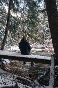 a person sitting on a bench in the snow at Auberge Yoga Salamandre in Lac-Brome