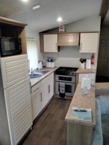 a small kitchen with white cabinets and a sink at 19 Laurel Close Highly recommended 6 berth holiday home with hot tub in prime location in Tattershall