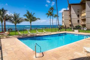 a swimming pool with chairs and the ocean in the background at Maalaea Kai 311 - Direct Ocean Front, Split AC in Wailuku