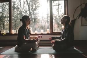 Due donne sedute in una sala di meditazione di fronte a una finestra di Auberge Yoga Salamandre a Lac-Brome