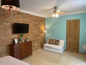 a bedroom with a couch and a tv on a brick wall at Residencial Jurerê Belo in Florianópolis
