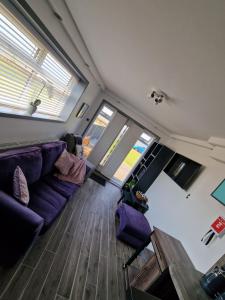 a living room with a purple couch and two windows at Seabreeze The Annexe in Blackpool