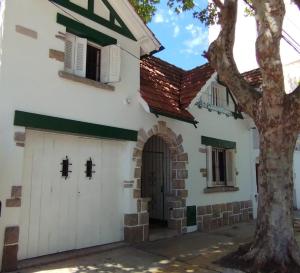 a building with a door and a tree at Maui Hostel in Mar del Plata