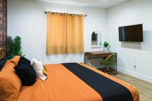 a bedroom with a bed and a desk and a television at The Relyn in Inglewood