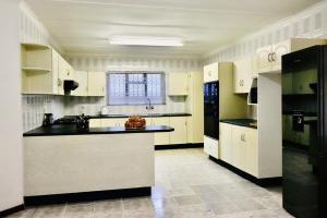 a large kitchen with white cabinets and black appliances at Lake Acres Guest House in Kokstad