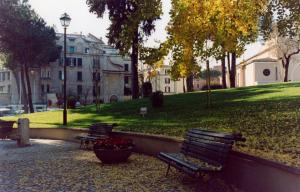 two park benches in a park with trees and buildings at Villa Fiorelli rooms in Rome