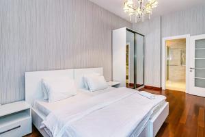 1 dormitorio con 1 cama blanca grande con lámpara de araña en Vip Apartment Zanzibar en Baku