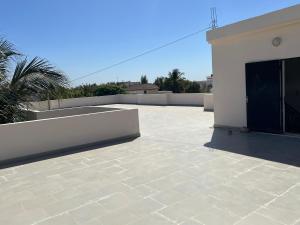 une grande terrasse avec un bâtiment blanc et une clôture dans l'établissement Residences Fama, à Mbour