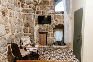 a room with a stone wall and a table and chairs at Hebi house in Acre