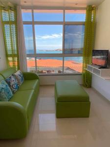 sala de estar con sofá verde y ventana grande en Apartamentos vista ao mar, en Praia Baixo