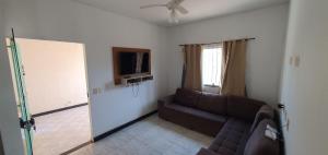 uma sala de estar com um sofá e uma televisão de ecrã plano em Casa Temporada Praiano em Guriri