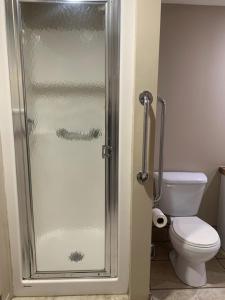 a bathroom with a toilet and a glass shower door at La Maison Tanguay in Saguenay