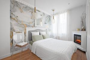 a white bedroom with a bed and a fireplace at Le Sapphire in Toulouse