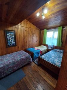 Dos camas en una habitación con paredes de madera. en Cabaña Martina, en Pucón