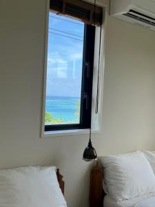 1 dormitorio con ventana y vistas al océano en senahahausub03 en Yomitan