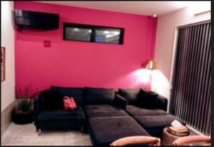 uma sala de estar com um sofá e uma parede vermelha em senahahausub03 em Yomitan