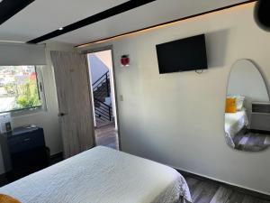 - une chambre avec un lit et une télévision murale dans l'établissement Hotel Daba Suites, à Chilpancingo de los Bravos