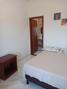 Schlafzimmer mit einem Bett und einem Holztisch in der Unterkunft Suítes da Alcy in Caraíva
