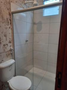 a bathroom with a glass shower with a toilet at Suítes da Alcy in Caraíva