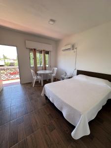 1 dormitorio con 1 cama blanca, mesa y sillas en Departamentos LT1, en Las Toscas