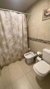 y baño con aseo y cortina de ducha. en Departamento TIERRA V en Salta