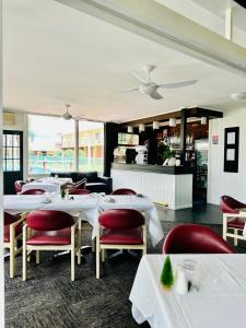 uma sala de jantar com mesas brancas e cadeiras vermelhas em Econo Lodge Gateway Tamworth em Tamworth
