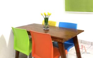 una mesa de madera con sillas coloridas y un jarrón de flores en Hospedaje Aldana Apartamento AURA Centro Histórico, en Tuxpan de Rodríguez Cano