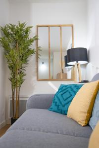 a living room with a couch and a mirror at Le Beverley Studio - Centre-ville - Fibre - Netflix in Blain