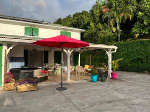 a patio with a red umbrella in front of a house at Ti Kay Bonè Bellefontaine in Fond Belle Fontaine