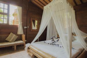 a bedroom with a bed with a mosquito net at Villa Lumbung in Ubud