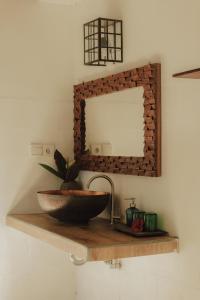 a bathroom with a sink and a mirror on a shelf at Villa Lumbung in Ubud