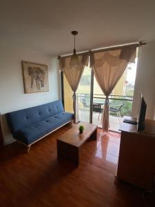 a living room with a blue couch and a table at Departamento Vistamar in Arica +6 photos
