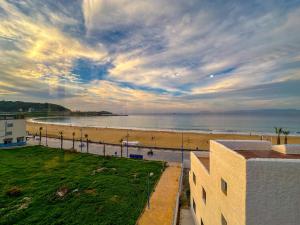 a view of a beach with a building and the ocean at Appartement el hichou 1 in Ksar es Sghir