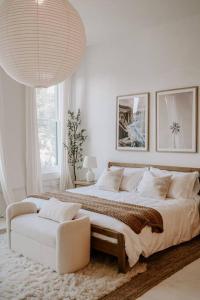 a white bedroom with a large bed and a chair at East Main Lofts - Coastal 201 in Madison