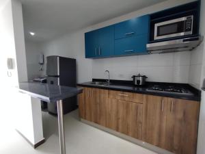 cocina con armarios azules, fregadero y microondas en Acogedor Apartaestudio Trento 21 Ciudad Jardín Popayan, en Popayán