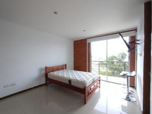 1 dormitorio con cama y ventana grande en Acogedor Apartaestudio Trento 21 Ciudad Jardín Popayan, en Popayán